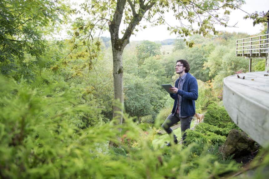 Young man using a digital tablet to analyse trees.
